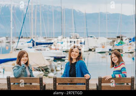 Outdoor portrait of happy mother and two young teenage girls resting by the lake. Image taken in Lausanne, Switzerland Stock Photo