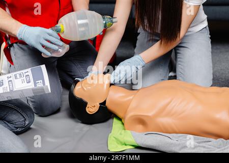 Woman holding breathing bag Ambu bag.Demonstrating CPR Cardiopulmonary resuscitation training medical procedure on CPR doll in the class.Paramedic dem Stock Photo