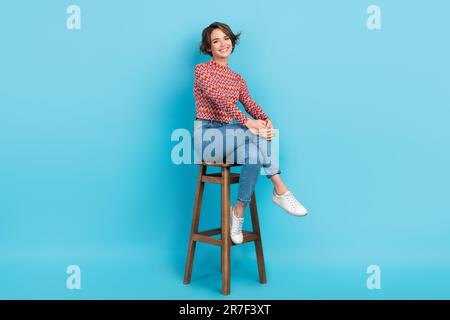 Photo adorable confident lady sit high bar chair order drinks bartender wear shirt pants sneakers isolated blue color background Stock Photo