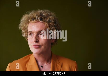 Portrait of gay man with blonde curly hair against studio backdrop Stock Photo