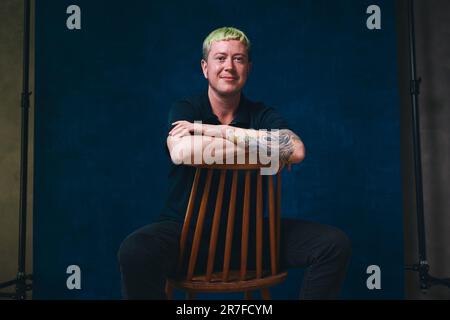 Portrait of gay man with tattoos sitting on chair Stock Photo