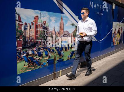 A man walks past a temporary construction hoarding in Mayfair, on 15th June 2023, in London, England. Stock Photo