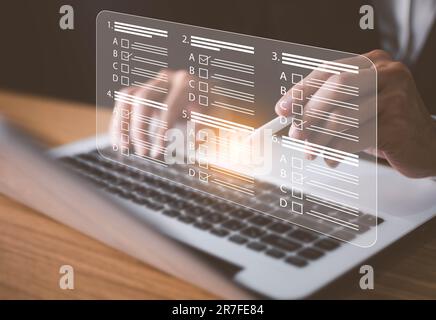 Man using laptop to do online survey online exam Choosing the right answer in the exam, filling out an online survey form. Answer the test questions. Stock Photo