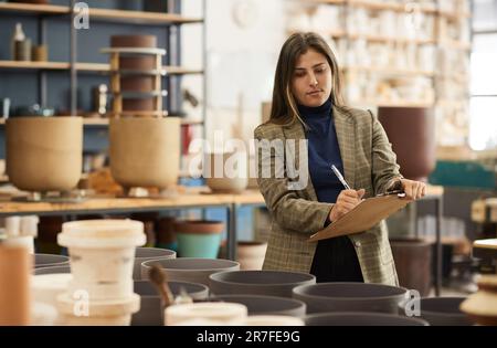 Ceramics workshop owner taking inventory in a pottery studio Stock Photo