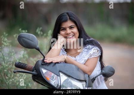 An Indian beautiful young girl with scooter smiling and having fun Stock Photo