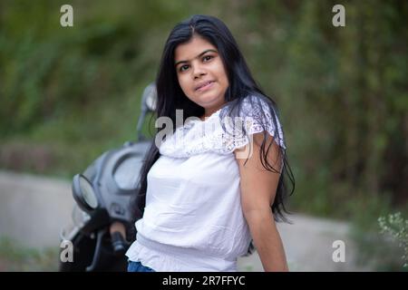 An Indian beautiful young girl with scooter smiling and having fun Stock Photo