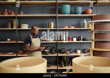 African ceramist using a digital tablet in a pottery workshop Stock Photo
