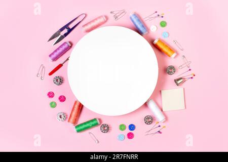Sewing threads, buttons, scissors and a round blank copy space on a yellow background in a top view Stock Photo