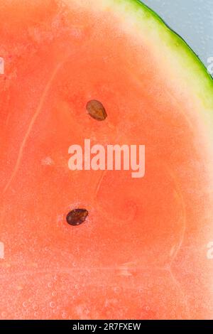 Close-up of juicy watermelon slice. Slice of ripe melon in sparkling water, close-up. Vertical macro image. Stock Photo