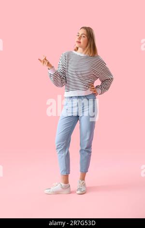 Young woman in striped sweatshirt snapping fingers on pink background Stock Photo