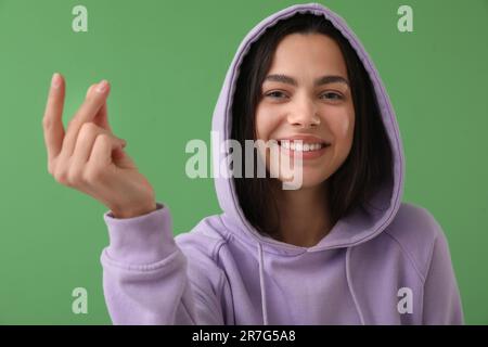 Beautiful young woman snapping fingers on green background, closeup Stock Photo