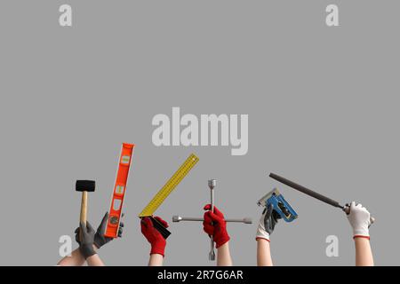 Female and male hands in gloves holding different construction tools on grey background Stock Photo