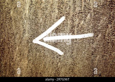 Pointer on a dirty background. White arrow on a background of dirt.Arrow sign drawn on a dry dirty white background.Dirt background texture and a draw Stock Photo