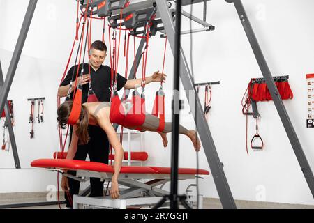 physical therapy, Physical rehabilitation, Health-improving exercises, doing exercises, decompression simulators. Rehabilitation exercises on red cord slings to restore pain-free movement patterns and enhance overall body functions Stock Photo