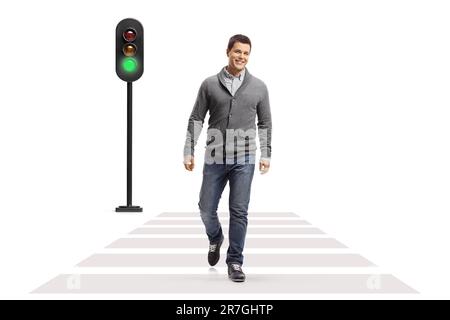 Full length portrait of a young smiling man walking at a pedestrian crossing isolated on white background Stock Photo