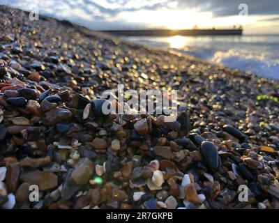 Looking Across a Decorative Stack of Different Coloured Stones, Pebbles and Cobbles at Hampton Stone Beach, Hampton Pier in the Distance. Stock Photo