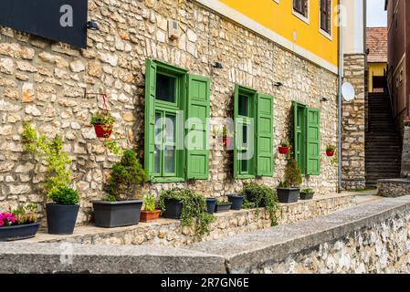 Beautiful green jalousie windows of renovated old building with stone walls. Stock Photo