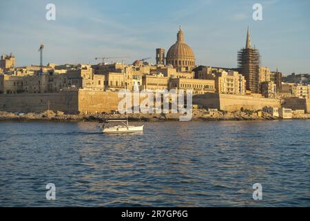 sail boat and Valletta city skyline with impressive dome of Carmelite Church at the sunset, Malta Stock Photo