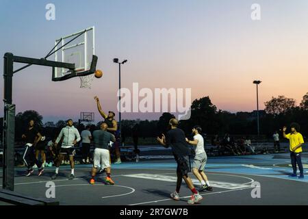 UK weather, Clapham, London, 15 June 2023: On a light summer evening after a hot day, basketball players make use of floodlit courts on Clapham Common to get some practice in. Credit: Anna Watson/Alamy Live News Stock Photo