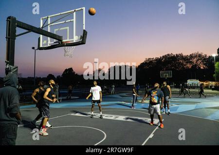 UK weather, Clapham, London, 15 June 2023: On a light summer evening after a hot day, basketball players make use of floodlit courts on Clapham Common to get some practice in. Credit: Anna Watson/Alamy Live News Stock Photo