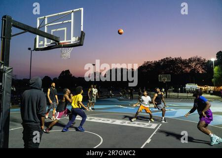 UK weather, Clapham, London, 15 June 2023: On a light summer evening after a hot day, basketball players make use of floodlit courts on Clapham Common to get some practice in. Credit: Anna Watson/Alamy Live News Stock Photo