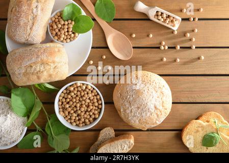 Soybean bread and seeds in bowls on wooden table with leaves and flour. Top view. Stock Photo