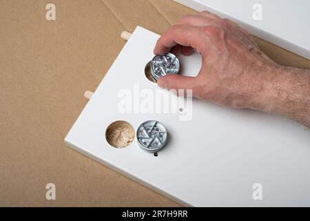 The furniture assembler assembles the furniture frame, insert the fixers, hands with DIY self assembly furniture. Stock Photo