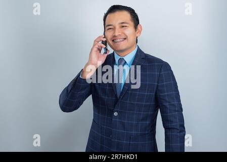 Businessman talks on the phone with a smile on his face, dresses in an entrepreneur's suit, one person Stock Photo