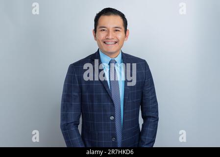 Young entrepreneur man, dressed for work in blue suit, shirt and tie smiles in front of the camera, brown skin Stock Photo