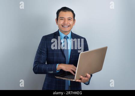 Young man with brown skin smiles dressed as a businessman with a laptop, blue clothes, one person Stock Photo