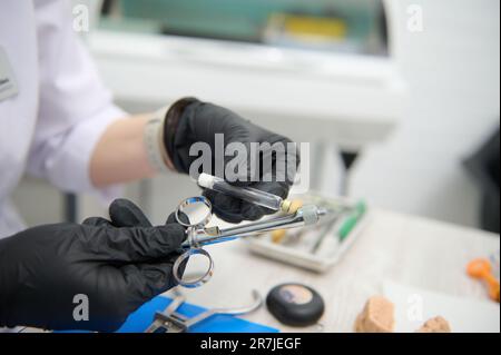 Close-up dentist hands placing a cartridge with dental anesthesia in syringe, preparing the anesthetic procedure Stock Photo