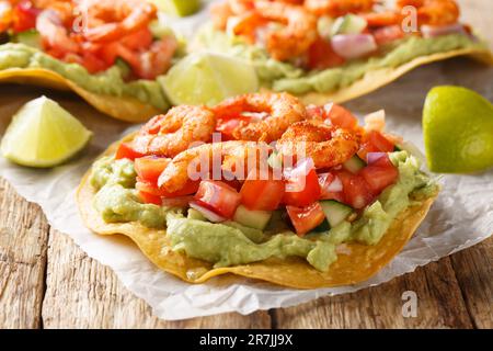 Freshly made shrimp tostadas topped with guacamole, onion, tomatoes, and cucumbers closeup on the wooden table. Horizontal Stock Photo