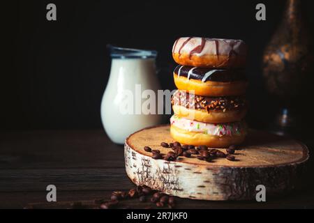 Stack of assorted donuts and jug of milk on a dark background. Stock Photo