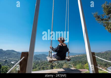 woman enjoying a rope swing in the hills of Chiang Rai Stock Photo