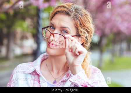 Sceptic woman holding glasses portrait in park Stock Photo
