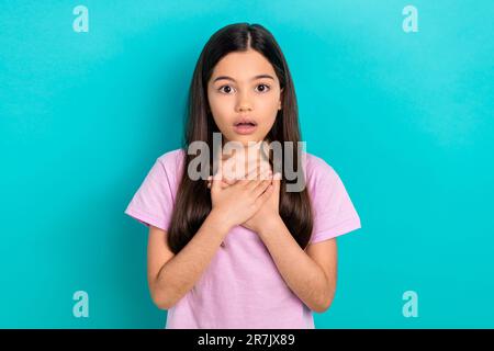 Photo of adorable shocked little child dressed pink t-shirt open mouth arms chest isolated teal color background Stock Photo