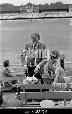 Cutting a Roast Chicken. Eton v Harrow annual cricket match at Lords Cricket Ground. Parents, father carving the cold roast chicken and mother preparing for their picnic  with their son. Its half time and time for lunch.  St Johns Wood, London, England circa June 1975. 1970s UK HOMER SYKES Stock Photo