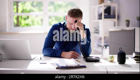 Adult Sitting At Corporate Desk Using Landline Telephone Stock Photo