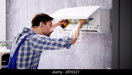 Portrait Of A Mid-adult Male Technician Testing Air Conditioner With Digital Multimeter Stock Photo