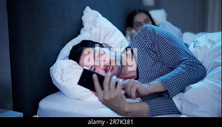Young Man Using Cellphone While Her Wife Sitting On Bed At Night Stock Photo