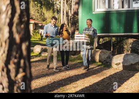 Friends carrying crates with freshly harvested organic vegetables at farm Stock Photo