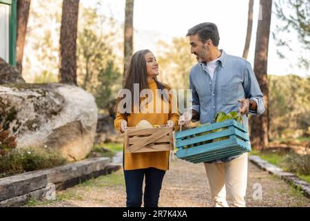 Man and woman carrying crates with freshly harvested organic vegetables Stock Photo
