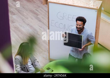 High angle view of businessman giving a presentation in office holding solar panel Stock Photo