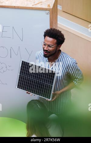 High angle view of businessman giving a presentation in office holding solar panel Stock Photo