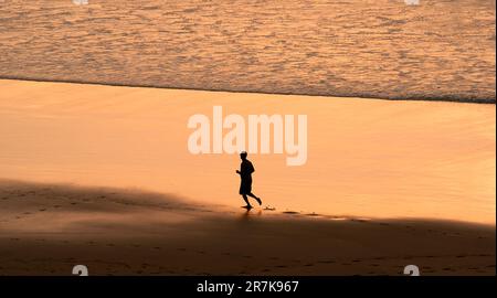 A man running along the beach at sunset or sunrise. Stock Photo