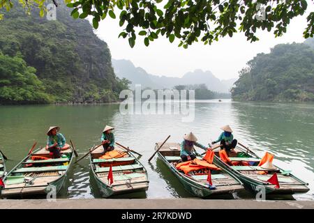 Ninh Binh, Vietnam-April 2023; View of women in sampan rowing boats for tourists on cave tours on Red River Delta in landscape of Trang An Stock Photo