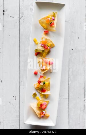 Yellow corn tortilla chips on a long platter topped with homemade salsa. Stock Photo