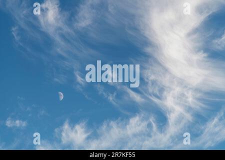 Image filling view of cirrus or feather clouds against a blue sky with a half moon between the clouds Stock Photo