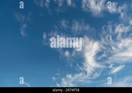 Image filling view of cirrus or feather clouds against a blue sky with a half moon between the clouds Stock Photo