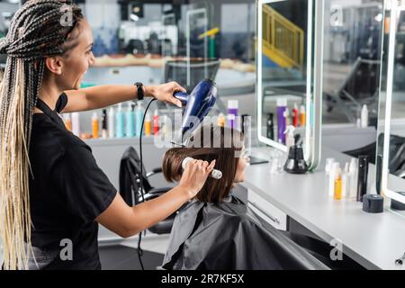 salon blow dry, professional hairdresser with round brush and hair dryer styling hair of happy female customer, brunette woman with short hair, beauty Stock Photo